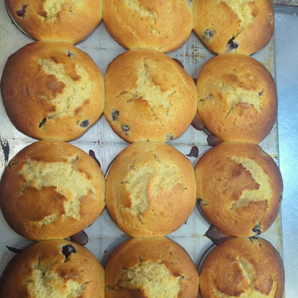 A close-up, overhead view of a tray of freshly baked golden-brown blueberry muffins.